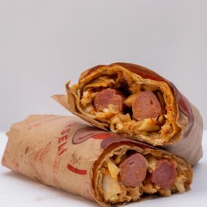 Close-up of savory shawarma wraps filled with meat and vegetables on a white background.