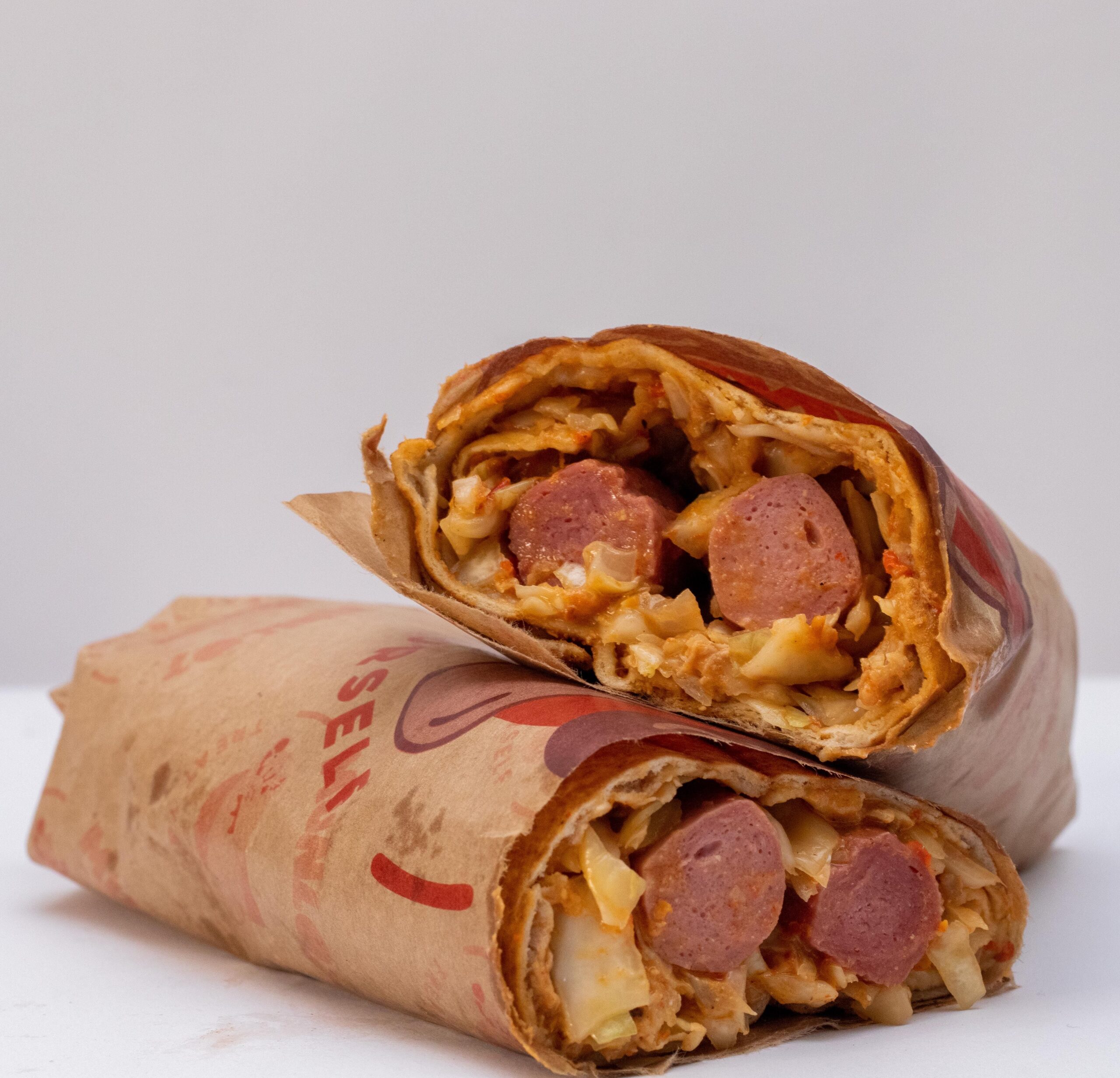 pexels photo 14639388 14639388 Close-up of savory shawarma wraps filled with meat and vegetables on a white background.