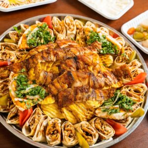 A mouthwatering close-up of a Middle Eastern grilled chicken and sandwich platter garnished with herbs.